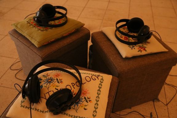 Three boxes with pillows, each having its own pair of headphones. On the closest pillow you can read the embroidered word ANTHROPOLOGY.