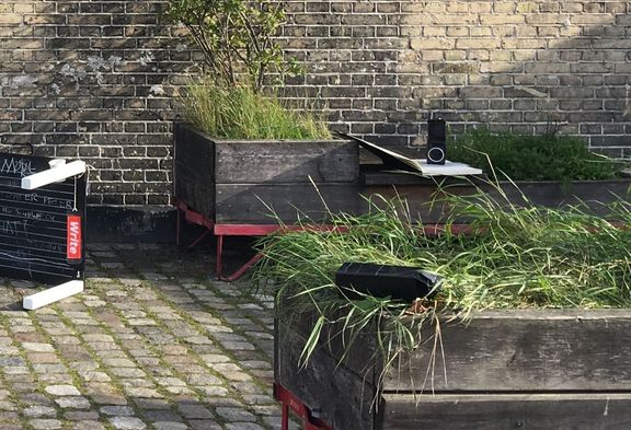 Two milk carton speakers inside, in front of a brick wall